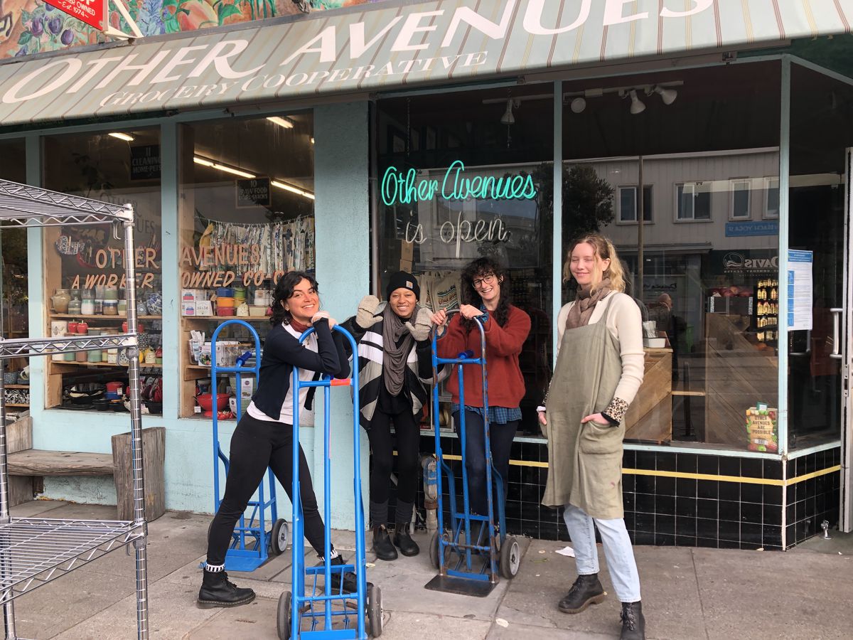 Four worker-owners in front of the grocery co-op, getting ready to open for the day