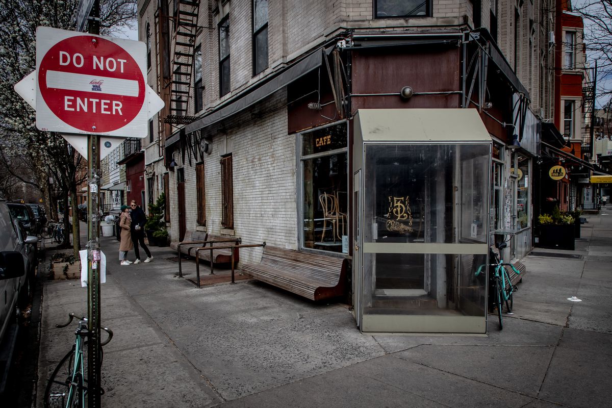A couple kisses next to a closed Five Leaves restaurant in Brooklyn