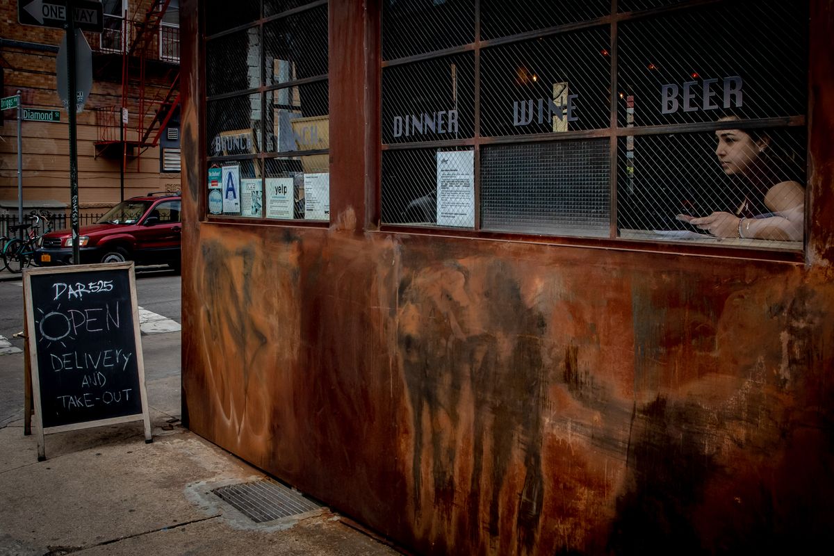 A woman looks through a restaurant window as she waits for customers