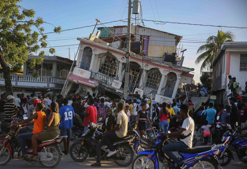 People gather outside the Petit Pas Hotel, destroyed by the earthquake in Les Cayes, Haiti, Aug. 14.