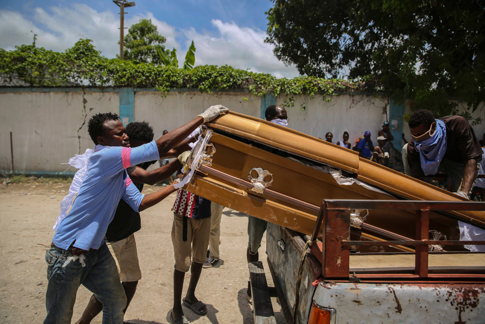 Men load into the bed of a truck the coffin containing the remains of Francois Elmay after recovering his body from the rubble of a home destroyed in the earthquake, in Les Cayes, Haiti, Aug. 18.