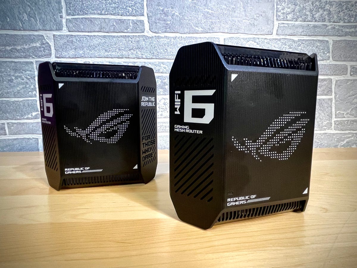 The Asus ROG Rapture GT6, the company's first mesh gaming router, sits side-by-side in a 2-piece configuration against a brick background. Each device looks more like a black-bodied PC tower than a Wi-Fi router.