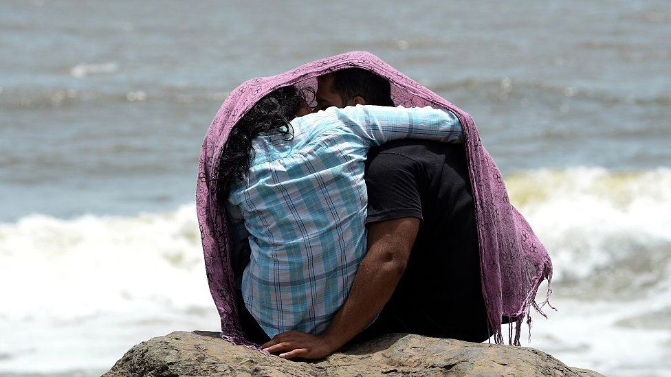 A young couple sit together on a rocky outcrop off the Arabian sea in Mumbai on July 3, 2015.