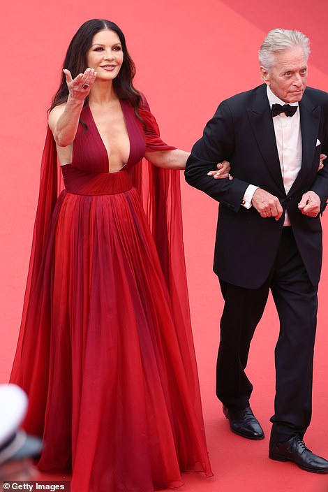 Stunning: Catherine, 53, put on a glamorous display in a plunging red gown with a one sleeve cape detail