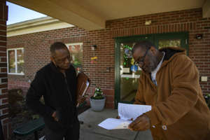 Community advocate Michael Thomas, on left, helps a man with housing questions in Steubenville.