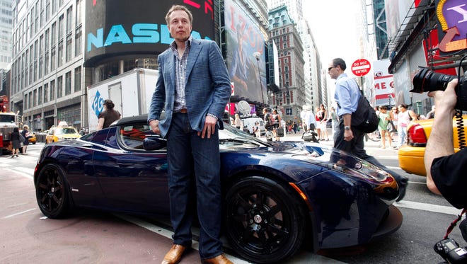 Elon Musk, CEO of Tesla Motors, poses with a Tesla car in front of Nasdaq following the electric automakerís initial public offering on June, 29, 2010, in New York.