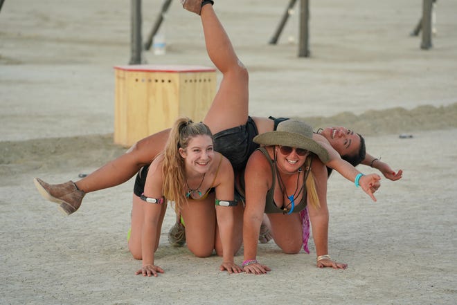Brooke "Mighty Mouse" Thayer of Seattle, left, helps hold up a friend as they goof around at Burning Man.