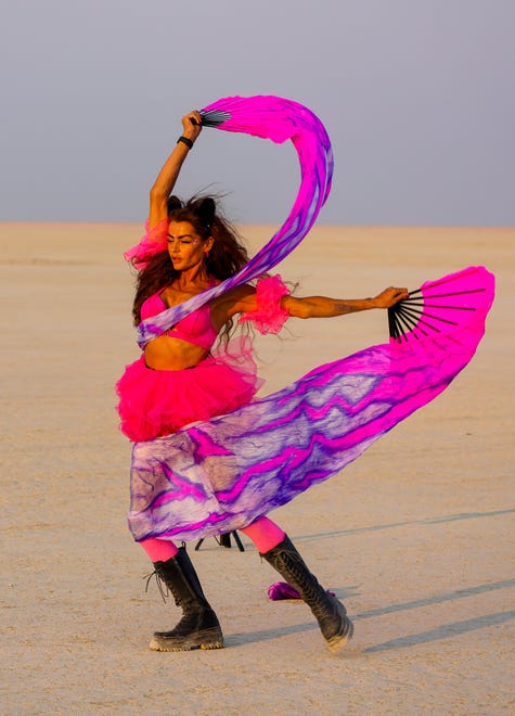 Eva Airy of Thailand dances at sunset in the Black Rock Desert at Burning Man.