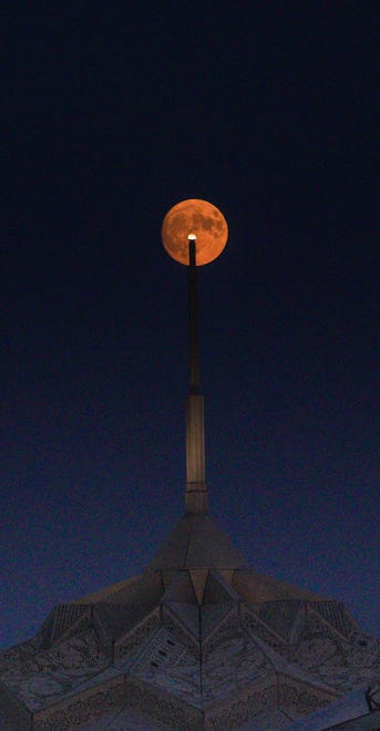 The nearly full moon rises over the Burning Man "Temple of the Heart."