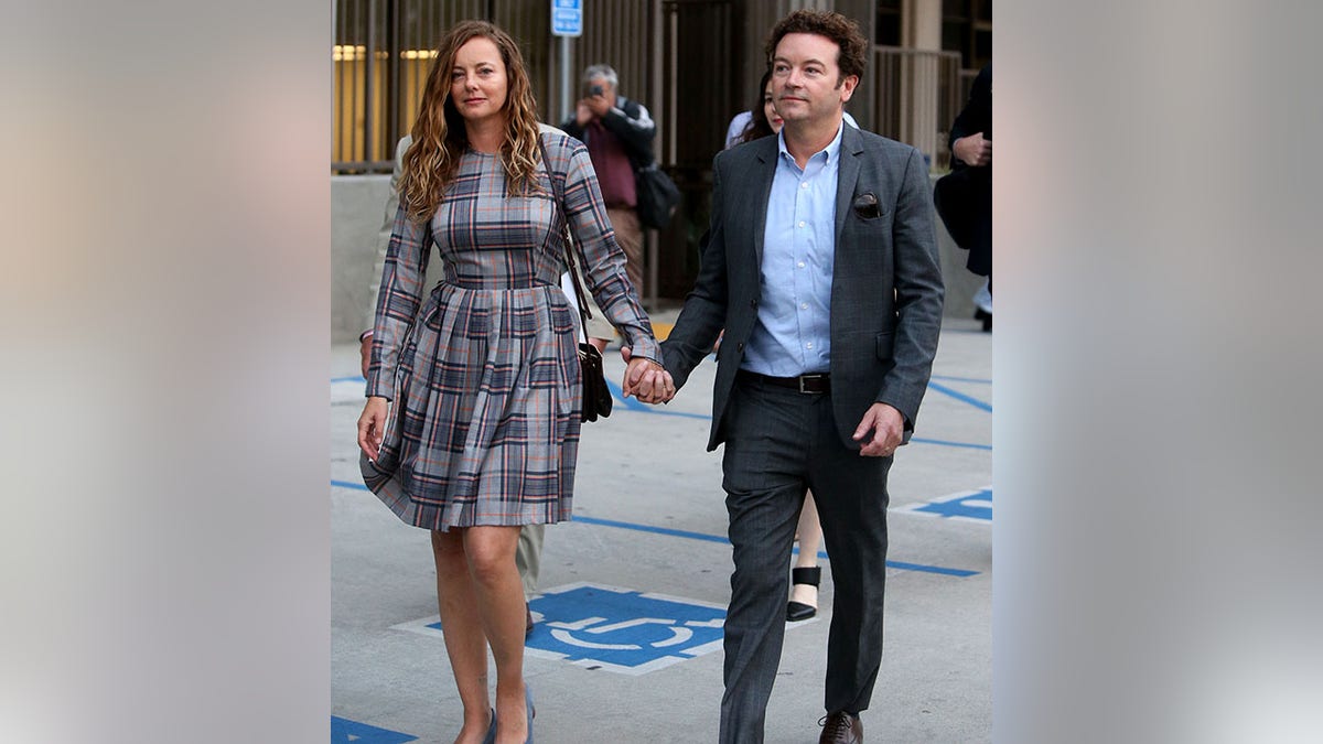 Bijou Phillips in a plaid dress holds Danny Masterson's hand as they walk out of the courthouse after his trial ended in a mistrial