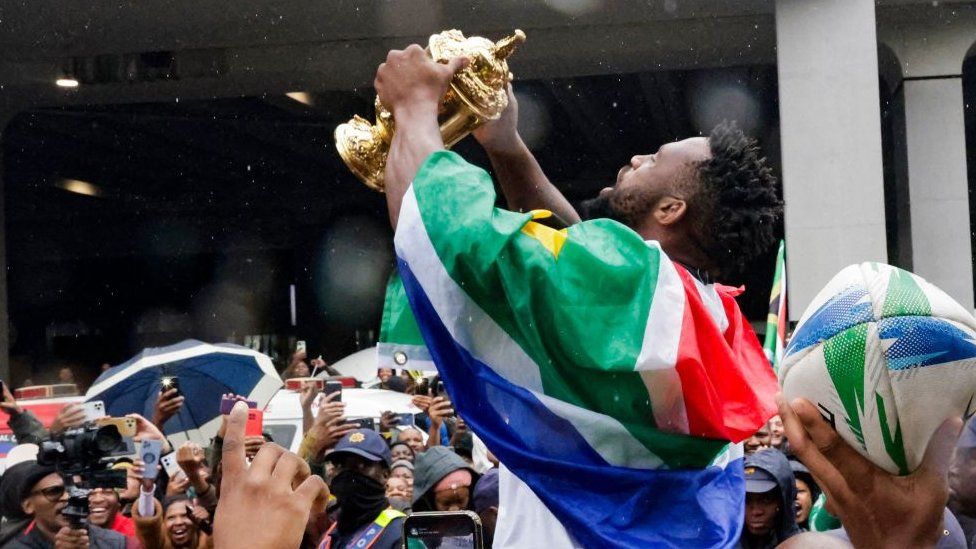 South Africa's flanker and captain Siya Kolisi holds the Webb Ellis Cup as he meets with supporters after the South African rugby team's arrival at the OR Tambo International airport in Ekurhuleni on October 31, 2023
