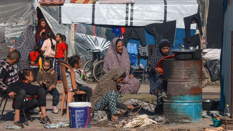 Displaced Palestinians cook in a makeshift outdoor kitchen near their tent in Rafah in the southern Gaza Strip