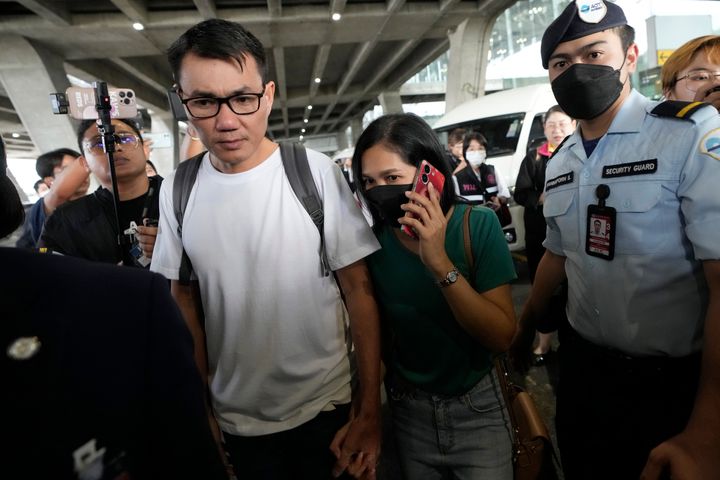 Owat Suriyasri, a Thai hostage who was freed from Hamas, holds the hand of his wife on his arrival Monday at an airport in Thailand. Twenty-three Thai hostages kidnapped by Hamas on Oct. 7 have been freed so far, and Thailand's foreign ministry says nine remain in captivity in Gaza. 
