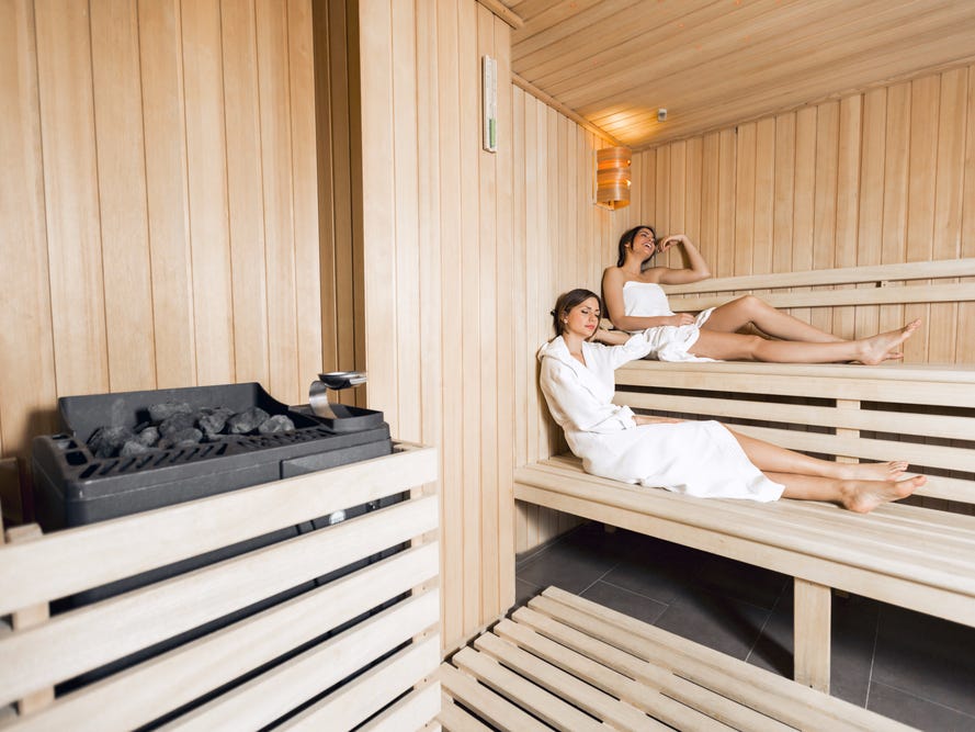 A sauna with two women reclining on the benches.