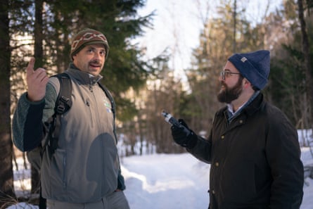 A man interviews another man among trees in a snowy park