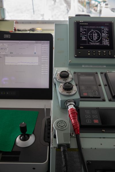 The controls on the bridge of the Ocean Link. A video screen shows a complicated output; there are many gauges and buttons.