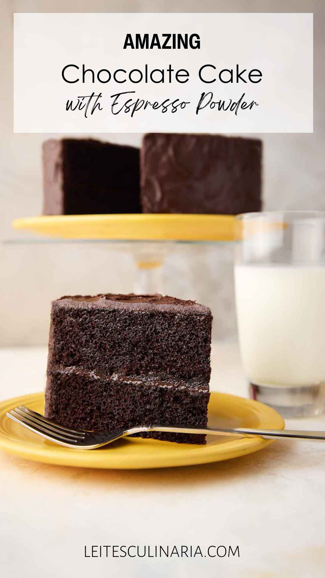 A slice of Hershey's chocolate cake with chocolate frosting on a yellow plate, with the remaining cake on a stand in the background.