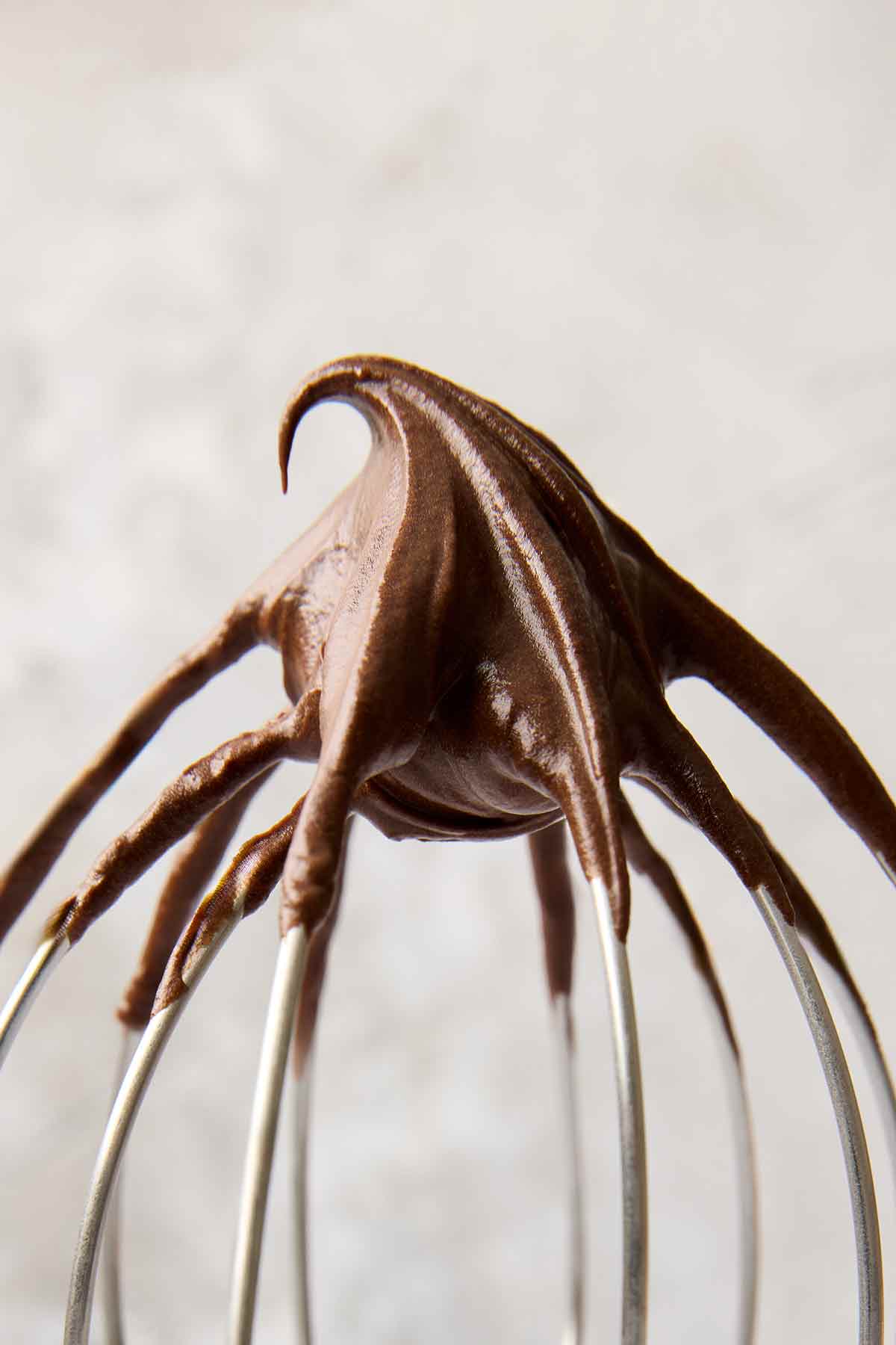 Chocolate frosting on a wire mixer whisk.