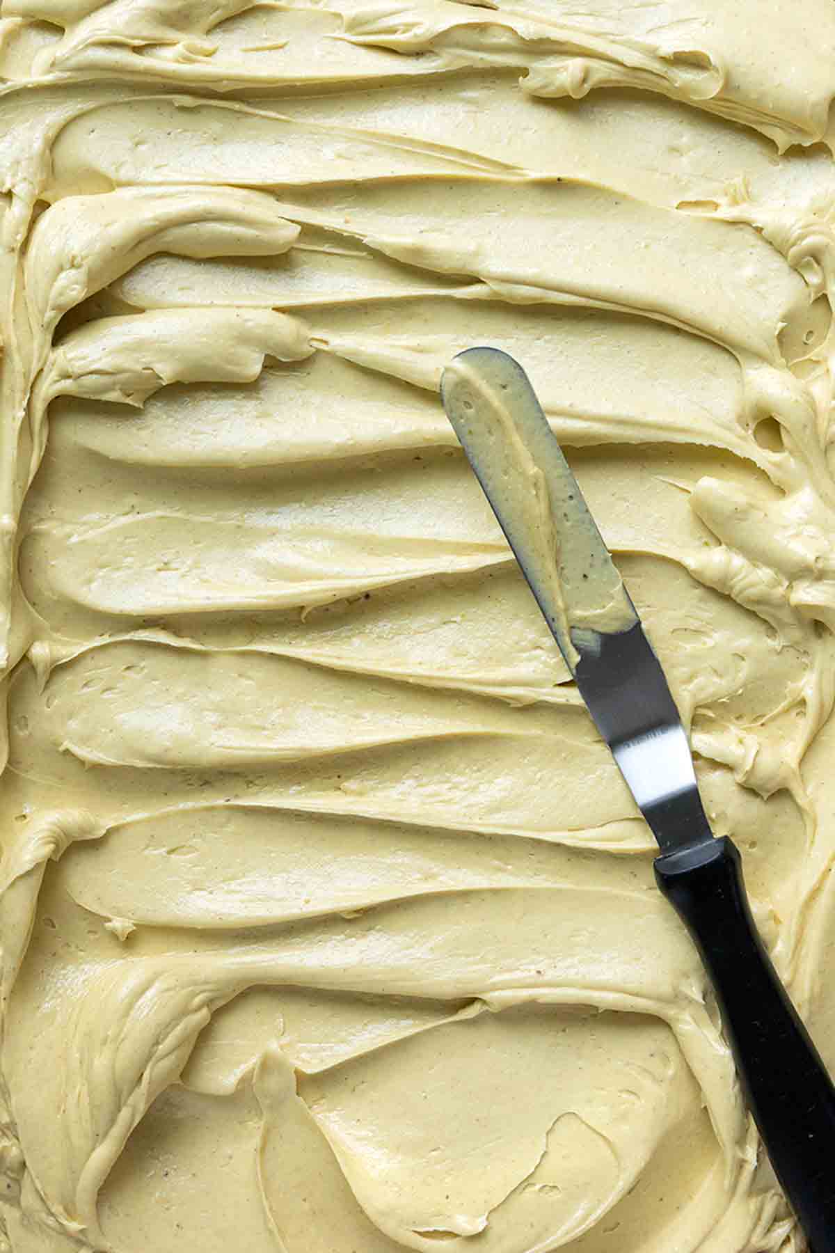 A large amount of pistachio buttercream frosting, swirled with a knife laying across it.