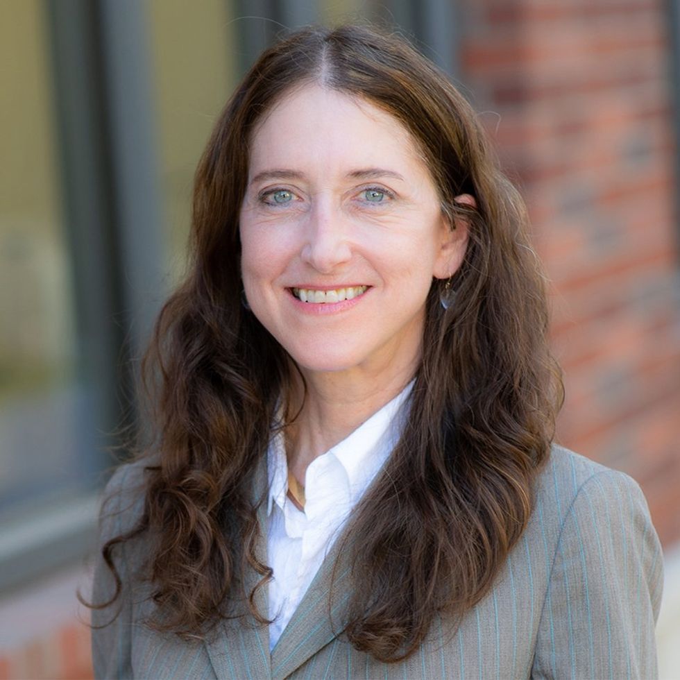 Photo of a smiling white woman wearing a suit.