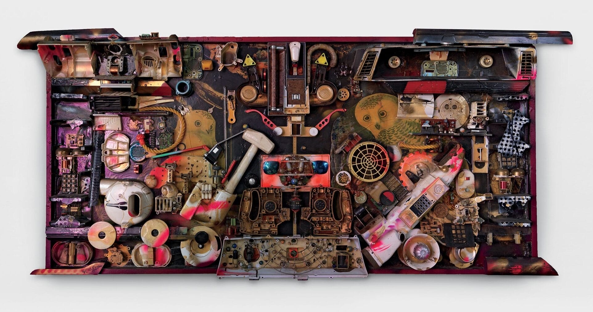a horizontal assemblage artwork made from found materials like sunglasses, spools, and other found parts