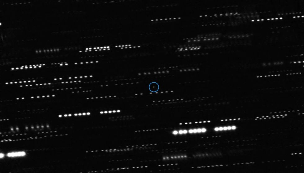 An image showing dotted lines of light of various intensities on a black background, with a small dot circled in blue at the center.