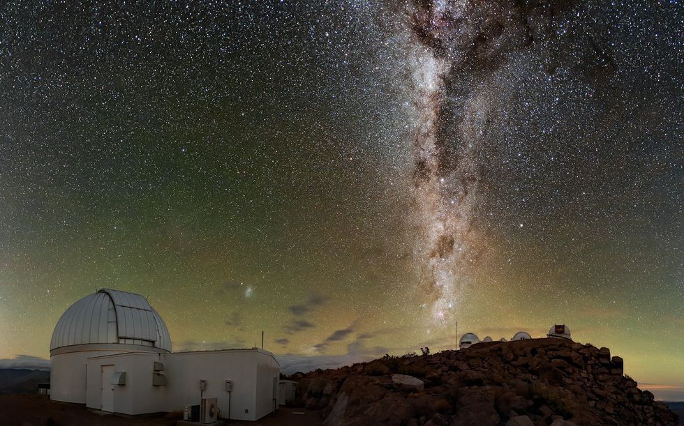 Nighttime photo of a domed building in the foreground with the Milky Way visible in the background.