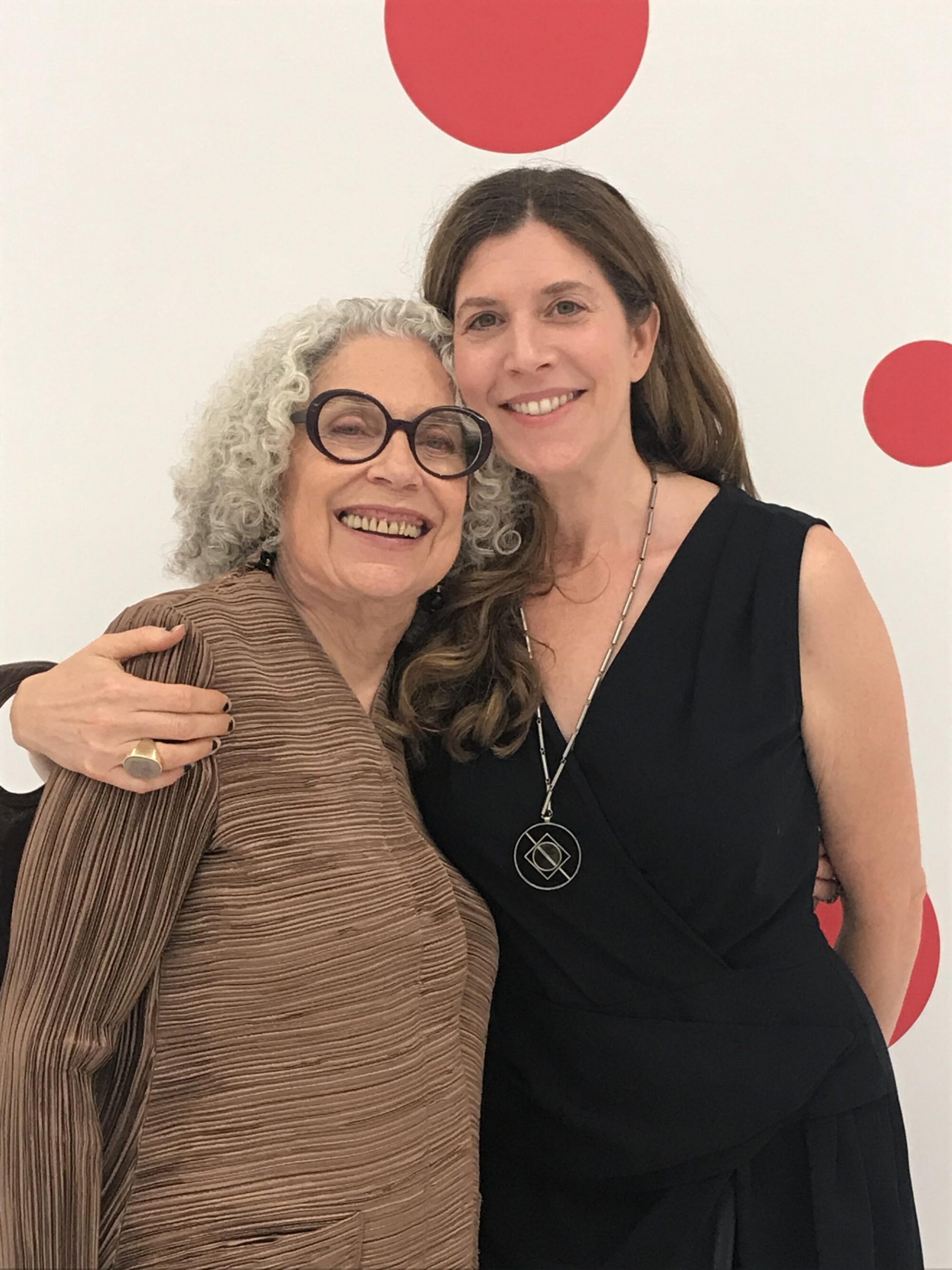 A woman stands with her arm around the shoulder of an older woman