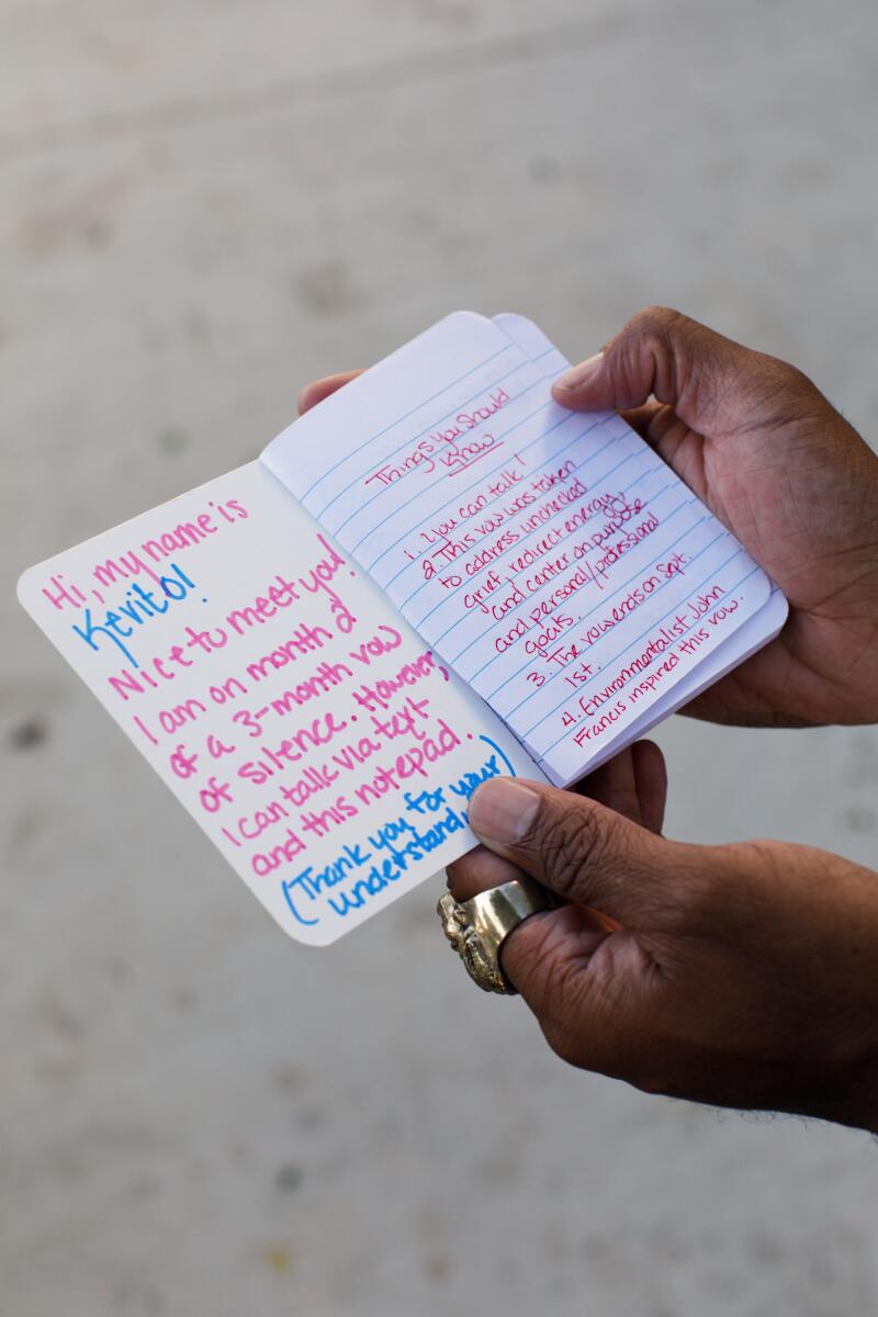 Kevito Clark holds a notepad he uses to communicate with people that has pre-written pages explaining why he's chosen not to speak for three months.