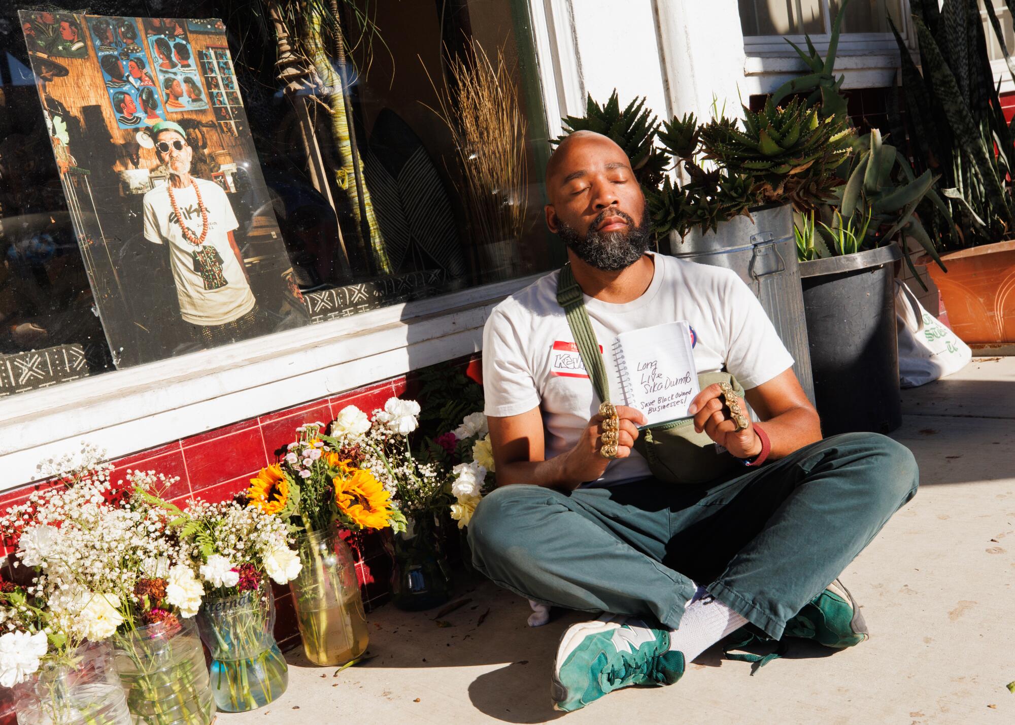 Kevito Clark sits outside next to a memorial of Sika Dwimfo while practicing his vow of silence.