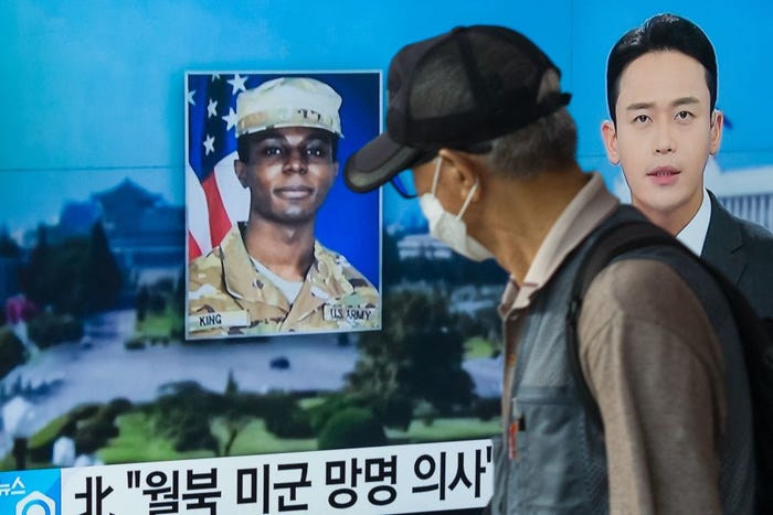 A man walks past a television showing a Korean news broadcast featuring a photo of US soldier Travis King.