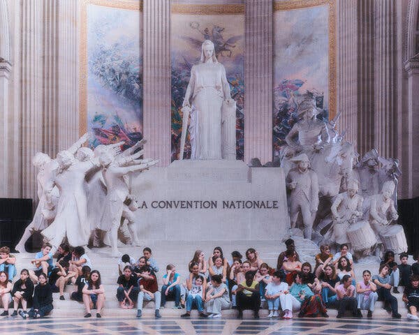 a group of children are clustered at the bottom of a monument in the Panthéon that says “La Convention Nationale.” The figure of a woman is at the top of the monument; on one side soldiers and drummers; on the other statesmen, their arms reaching up to her.