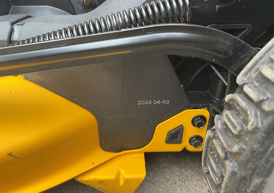 The date code is printed on the left side of the mower, above the rear wheel