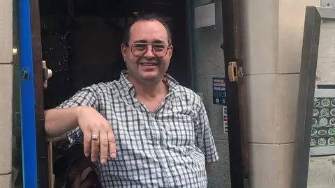 James Fitzgerald / BBC Riad stands in the doorway of his restaurant