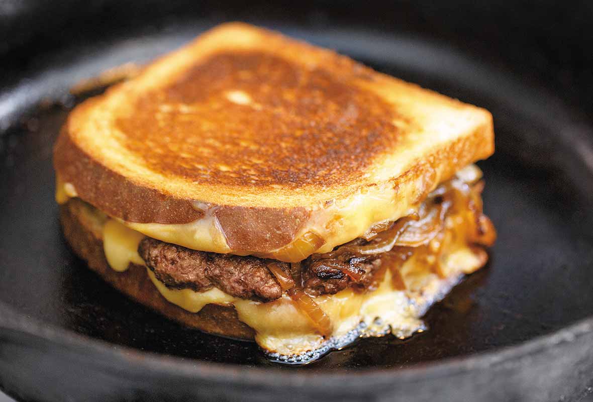 A patty melt sandwich filled with ground beef, caramelized onions and cheese.