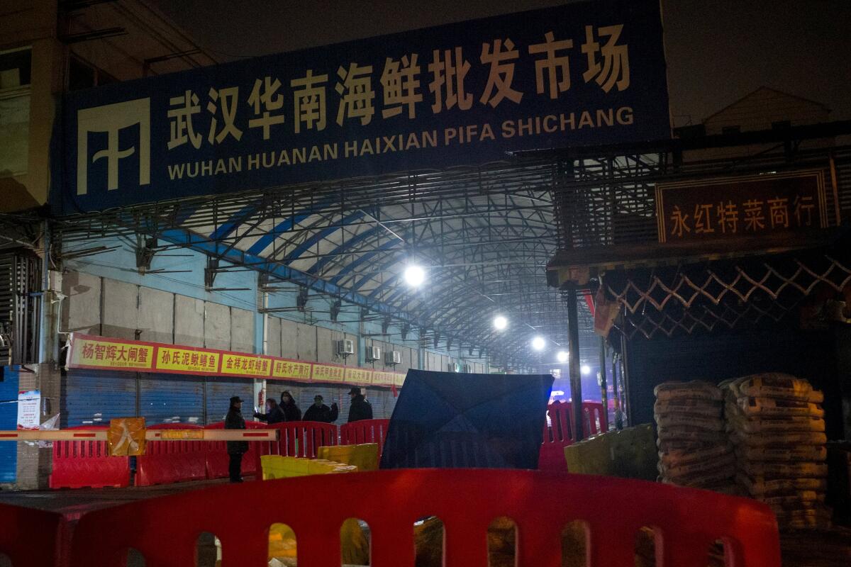 Security guards stand in front of a large warehouse at night. 