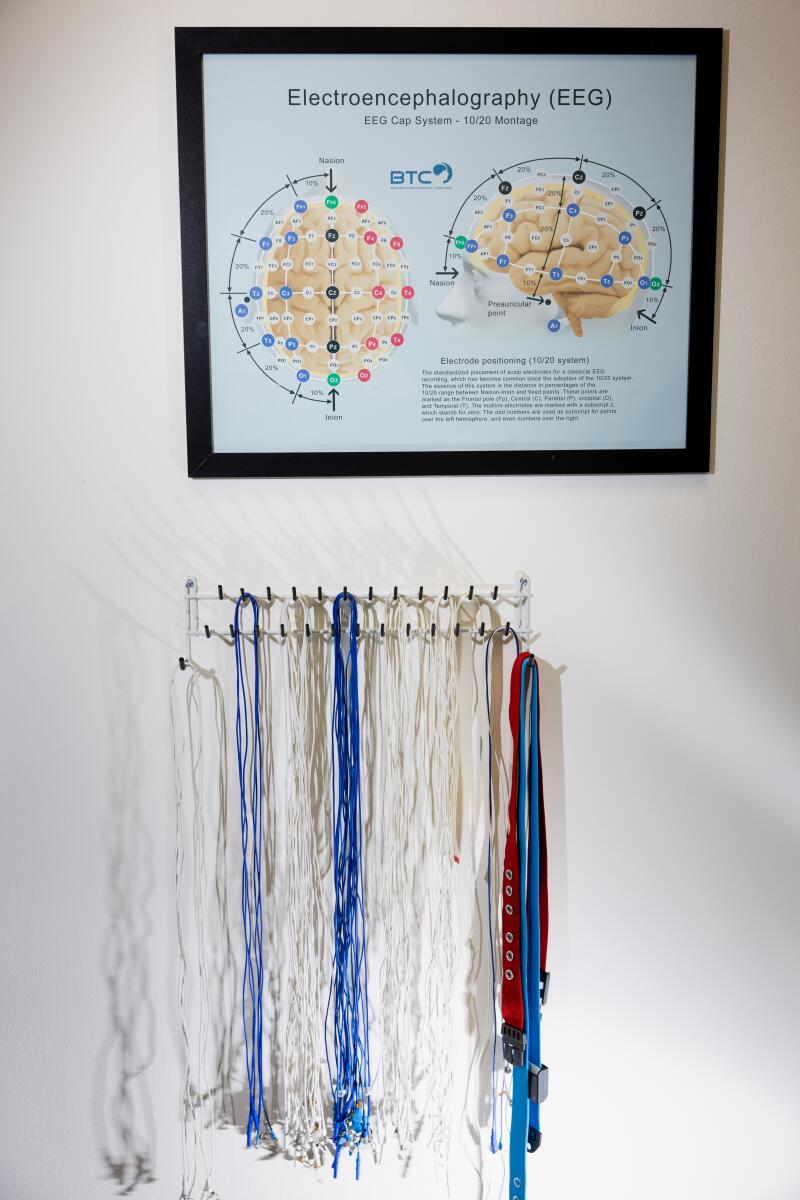 Electrodes hang on a wall below a chart about EEGs