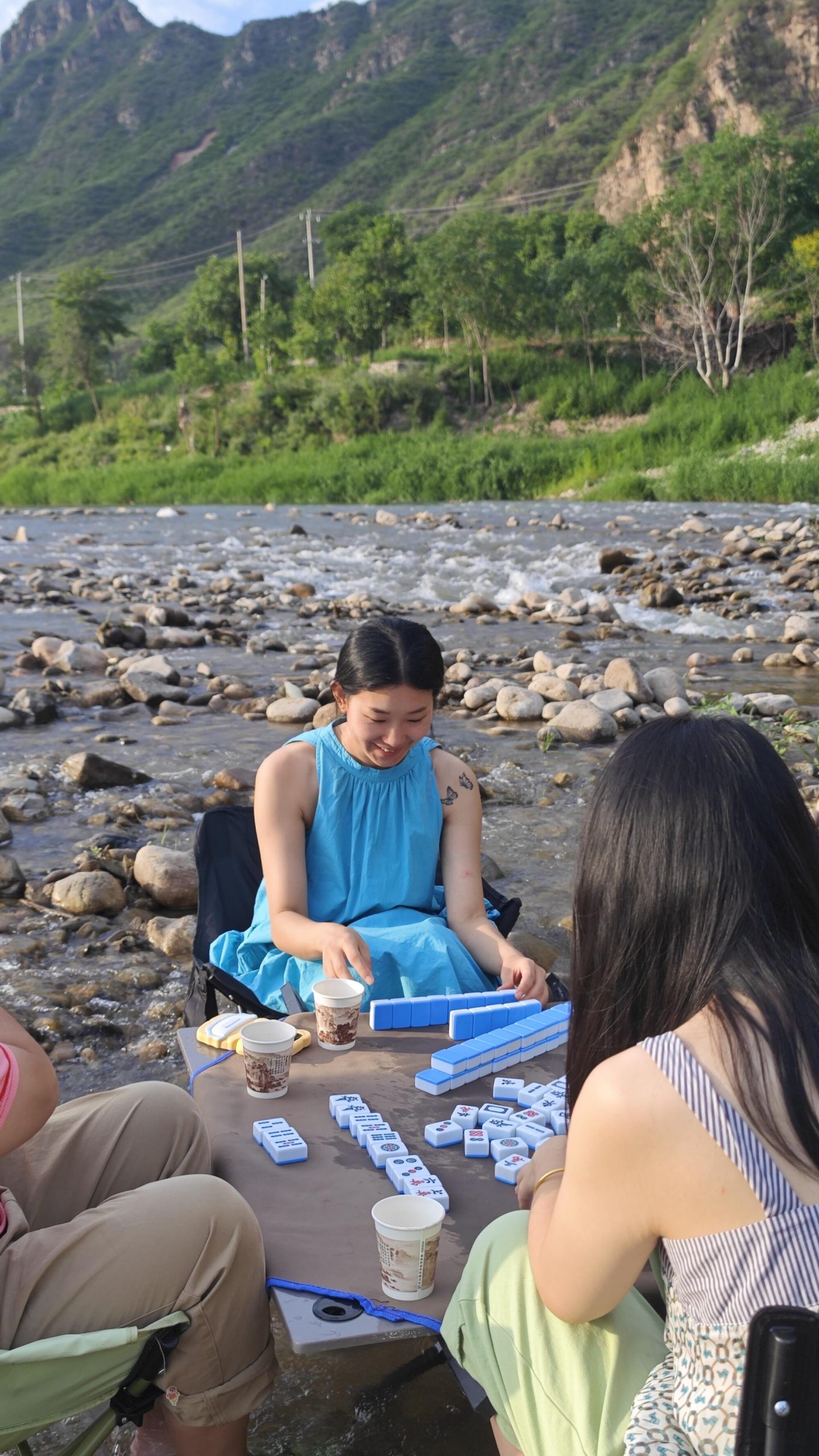 Young people sit outside playing mah-jongg.