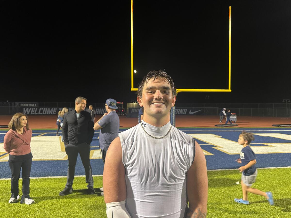 San Juan Hills quarterback Timmy Herr smiles while standing on a football field.