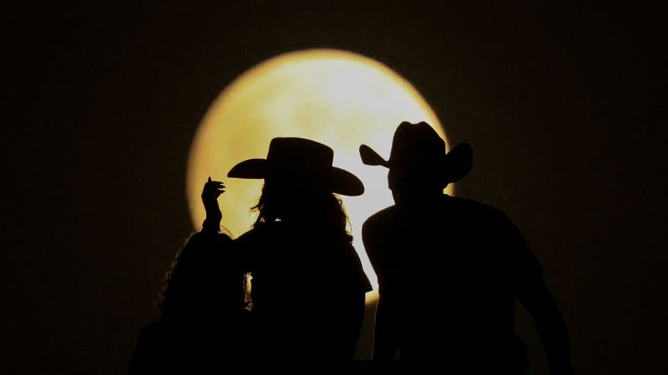 People look at the full moon on Tuesday at the Samalayuca Dunes on the outskirts of Ciudad Juarez, Mexico. - Jose Luis Gonzalez/Reuters