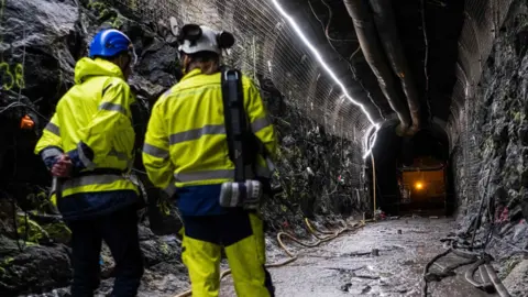 Getty Images Two construction workers stand in a tunnel inside the underground  geological nuclear waste disposal facility in Finland 