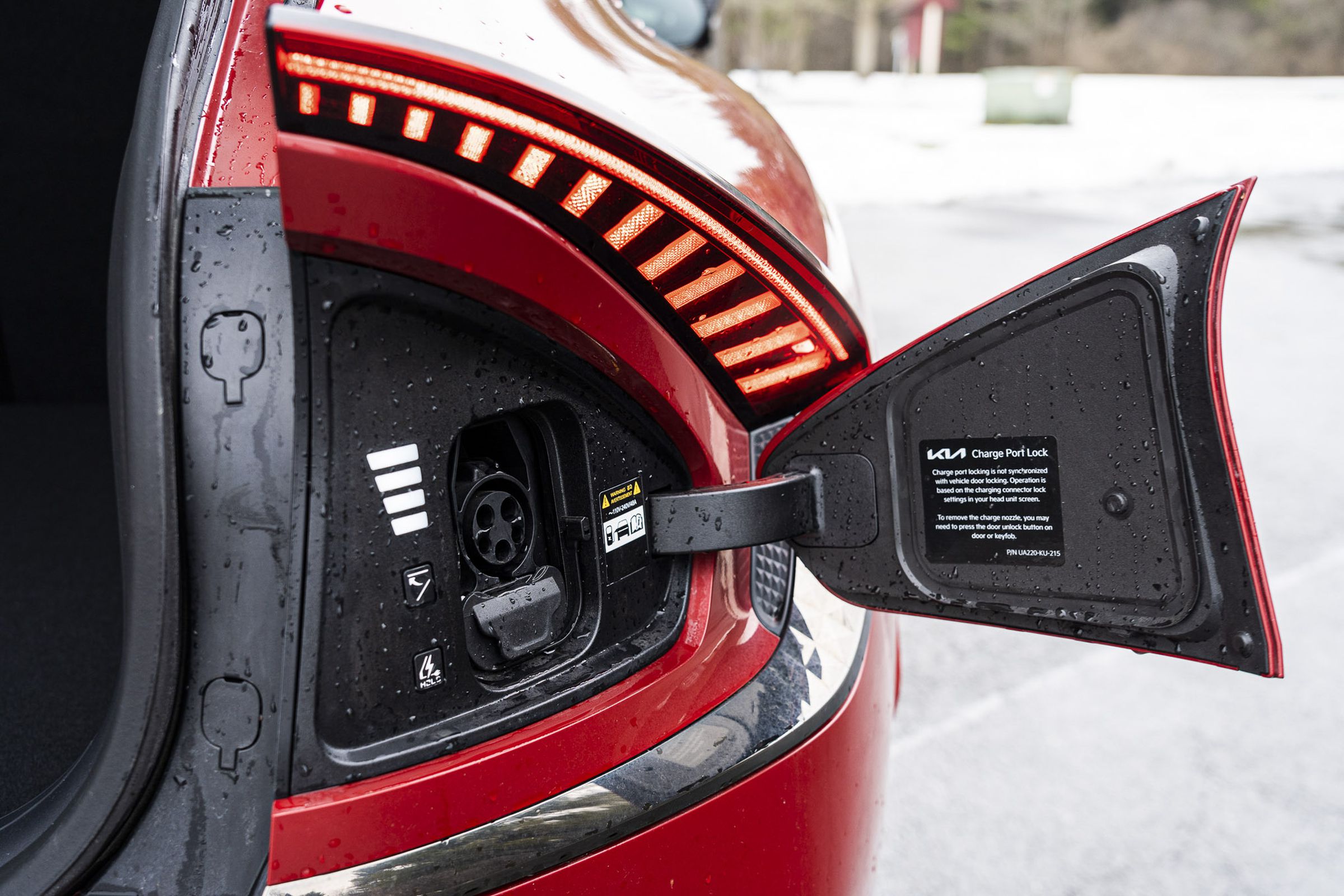 Close-up of a CCS Combo charge port on the rear right side of a red Kia EV6, hatch opened