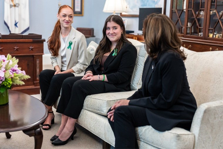 From left, Ella Seaver, and Emma Ehrens sit next to Kamala Harris on a couch