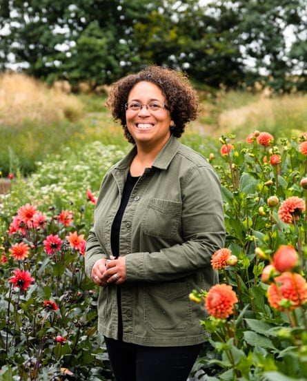 A woman stands between rows of dahlias