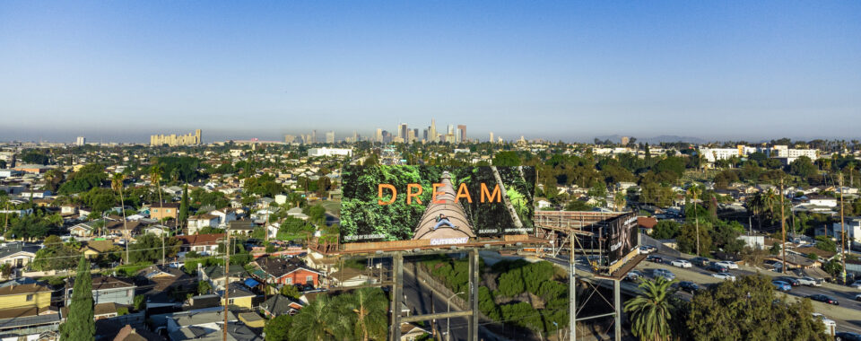 almost blending into the landscape surrounding it, a billboard shows a large tree and text that reads, "DREAM" in orange text