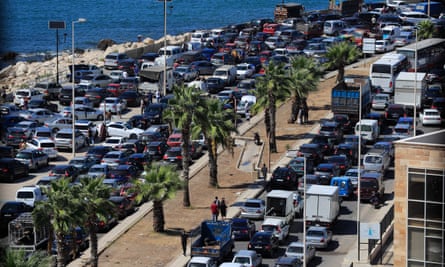 Cars fill lanes of traffic on a road next to the sea