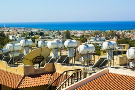 Boilers and solar panels on flat roofs, with the sea in the distance