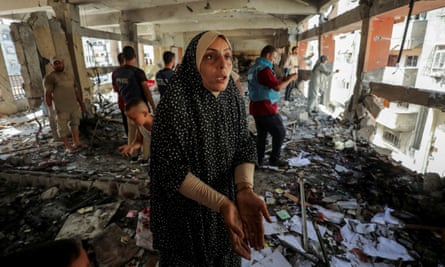 A Palestinian woman reacts as she inspects the damage to a school sheltering displaced people in Gaza City after it was hit by an Israeli strike