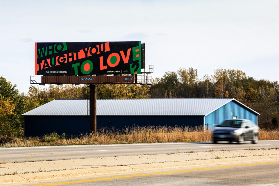 in black, red, and green, a billboard reads, "who taught you to love?"