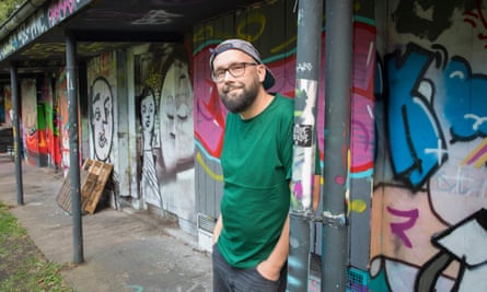 Man in green T.shirt with graffiti behind